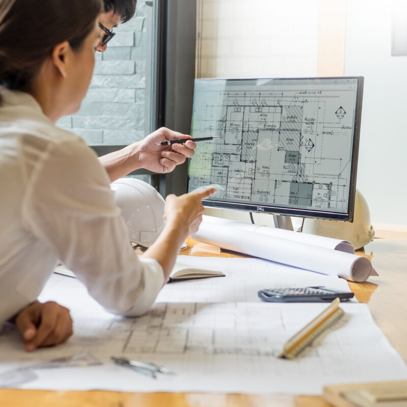 professional architect designer structural engineer team colleagues working office looking computer discussing their custom steel frame home building checklist.