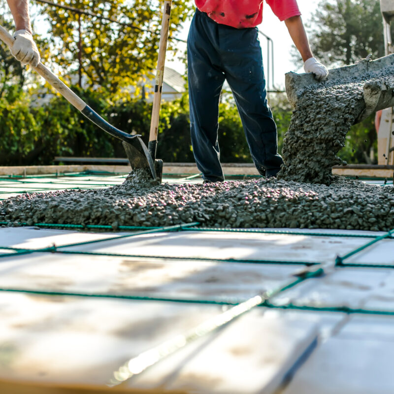 ready-mix-truck-pouring-wet-cement-two-workers-attending-an-engineered-slab-pour