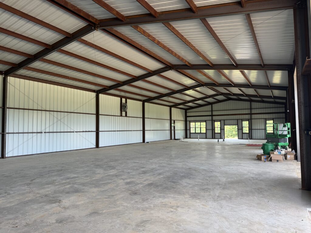 per-engineered metal buildings like this interior with red iron roof truss system and purlins, sheet metal sides and roof